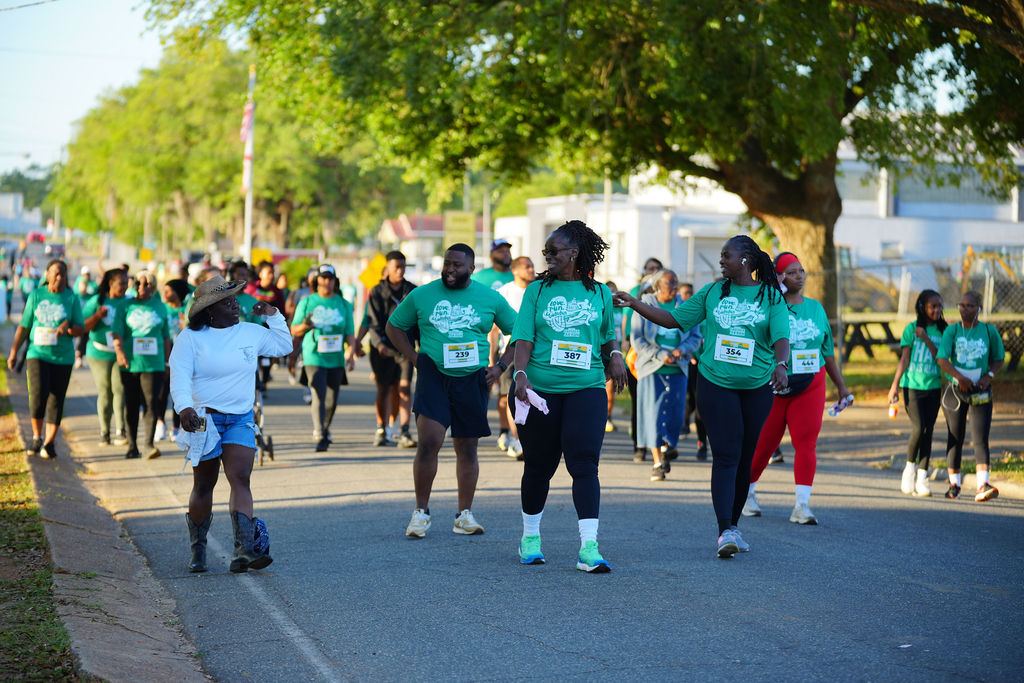 Walkers and runners in green shirts stretch down the road at the 2026 run